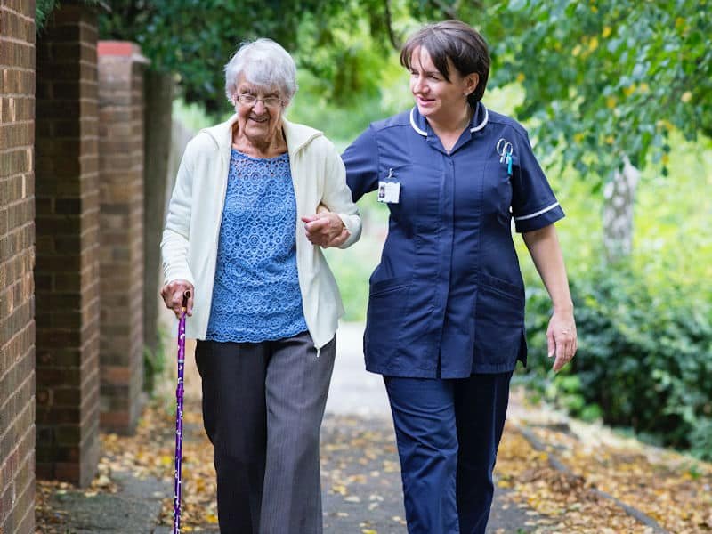 A nurse at Cartrefi Cymru helping an elderly lady to walk.